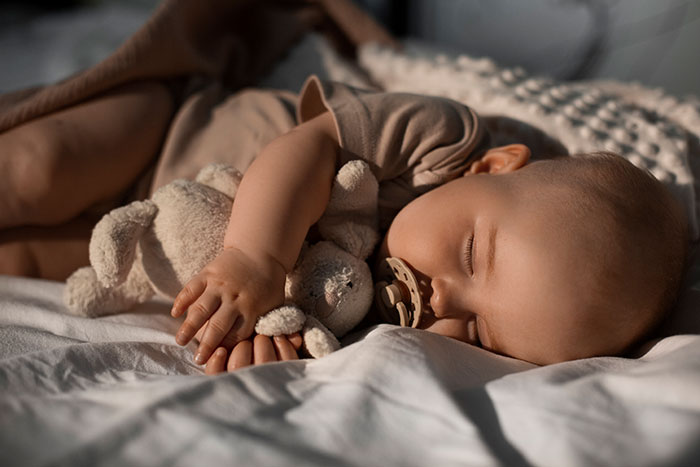 Sleeping baby holding a stuffed animal, symbolizing innocence and survival after horrifying kidnapping experiences.