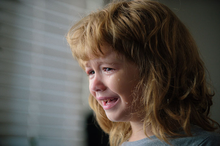Young child crying with tears, showing fear and distress related to kidnapping survivor experiences.