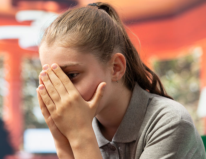 Young woman covering her face with hands, portraying fear and trauma related to kidnapping survival experiences.