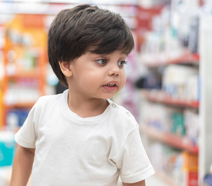 Young child in a white shirt looking aside in a store aisle, illustrating survival from kidnapping experiences.