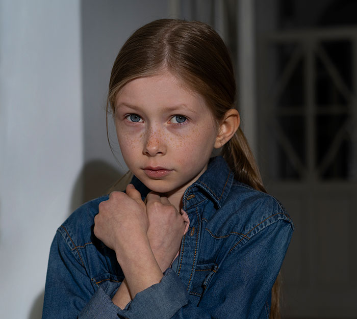 Young girl with a fearful expression wearing a denim jacket, depicting a kidnapping survivor's horrifying experience.