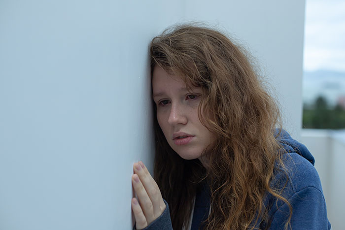 Young woman looking distressed and leaning against a wall, portraying a kidnapping survivor's horrifying experience.
