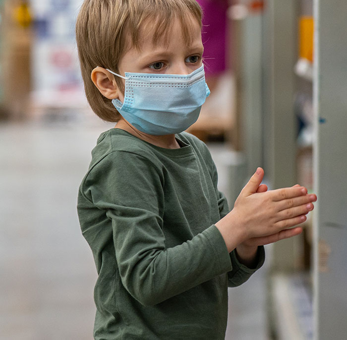 Young boy wearing a face mask inside a store, representing embarrassing moments parents experience with their kids.