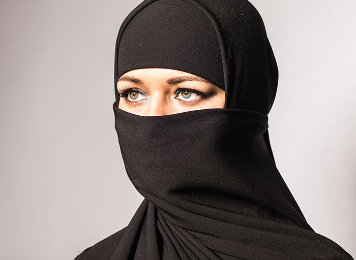 Woman wearing a black niqab with visible green eyes looking to the side, illustrating moments parents will never forget.