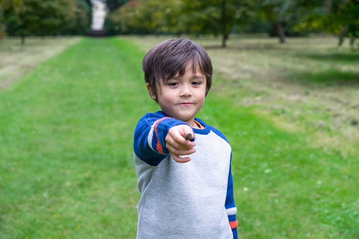 Young boy pointing forward outdoors, capturing a candid moment related to embarrassing moments parents experience with kids.