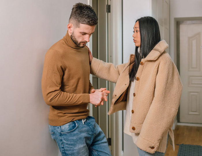 Man looking down and upset while woman comforts him in a hallway, reflecting relationship struggles with fiancee&rsquo;s kids.
