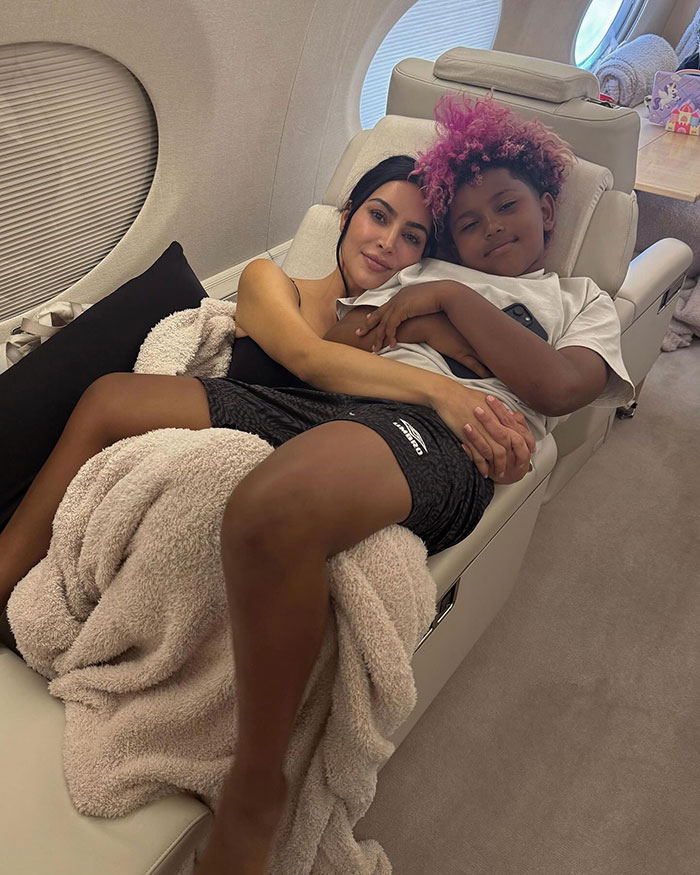 Kim Kardashian relaxing with daughter North West on a private jet, sparking discussion over North wearing a corset at age 12.
