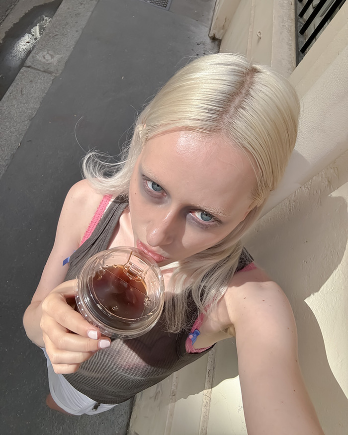 Young woman with dark under-eye makeup showing the new tired girl beauty trend popular among Gen Z women.