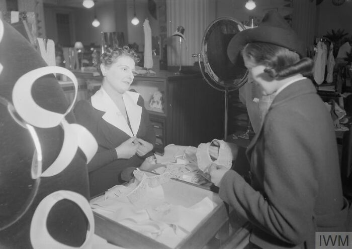 British women shopping for fashionable clothing during WWII restrictions, showcasing style despite wartime limitations.