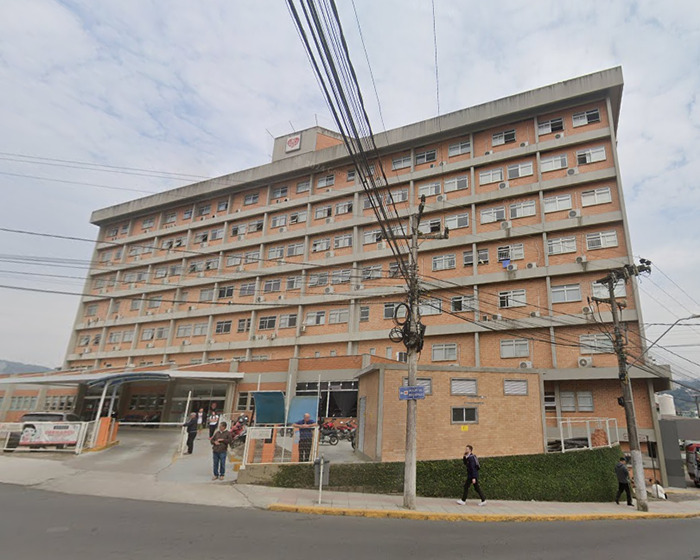 Large multi-story hospital building exterior with people walking outside, related to law graduate passing after CT scan.