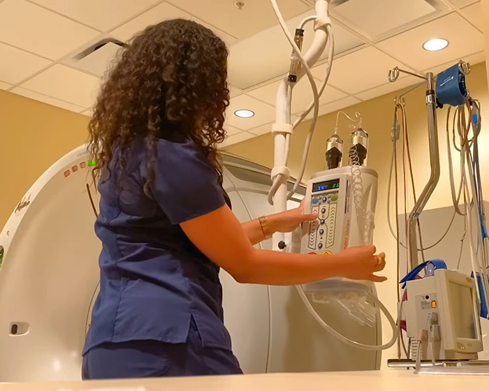 Medical professional adjusting equipment near CT scan machine in a hospital setting related to routine CT scan incident.