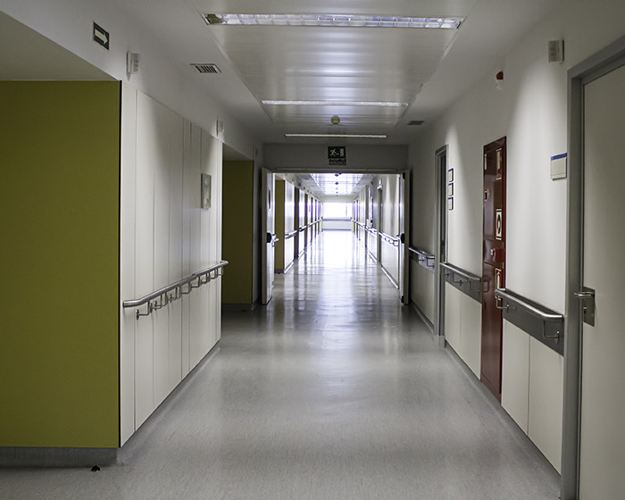 Empty hospital corridor with handrails and closed doors symbolizing routine CT scan and medical justice concerns.