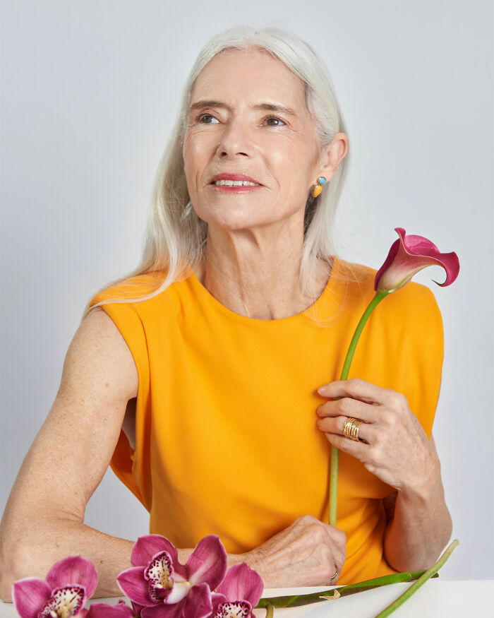 Older woman in a bright orange top holding flowers, illustrating the critical point when your body starts to age rapidly. Older woman in a bright orange top holding flowers, illustrating the critical point when your body starts to age rapidly.