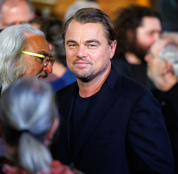 Leonardo DiCaprio at a public event with a focused expression, linked to PDA-filled yacht trip with girlfriend fans discuss.
