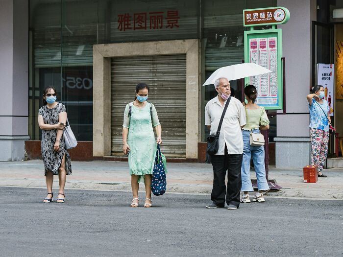 People wearing masks standing on a street in China amid rising chikungunya outbreak and global risk warnings.
