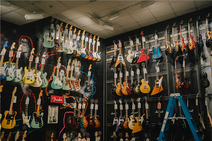 Wall filled with various electric guitars and amplifiers in a music store near Boston Marathon memorabilia. - 15