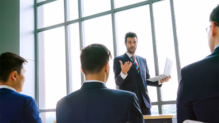 Man in suit giving a presentation to a group, discussing experiences related to the Boston Marathon event. - 2