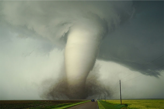 Massive tornado on open road under dark stormy sky, illustrating unexpected dangers like those at the Boston Marathon. - 3