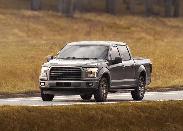 Grey pickup truck driving on a rural road, illustrating truck drivers’ terrifying road encounters and nightmares.