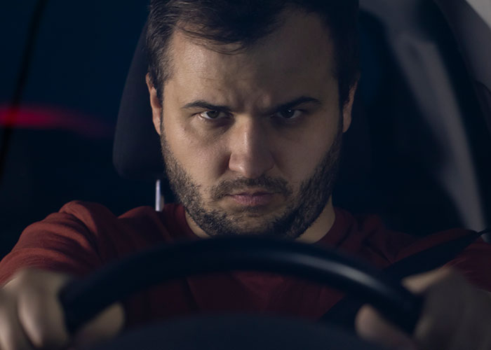 Truck driver gripping steering wheel tightly, focused and tense during a terrifying road encounter at night.