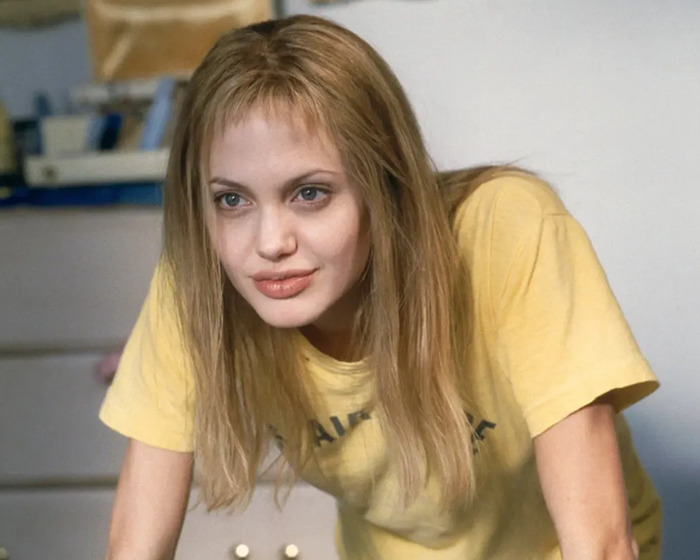 Young woman with tousled hair and minimal makeup showcasing the new tired girl beauty trend popular among Gen Z women.