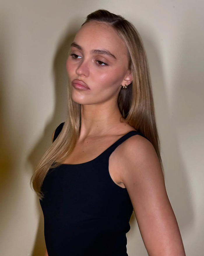 Young woman with long hair wearing a black top showing the new tired girl beauty trend popular among Gen Z women.