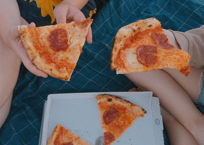Two people holding pepperoni pizza slices over a pizza box, illustrating accidental loopholes discovery moments.