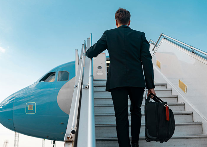 Man in suit carrying suitcase boarding airplane, illustrating people discovering loopholes and using them effectively.