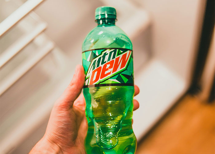 Hand holding a Mountain Dew bottle, illustrating a creative loophole discovery used to gain an advantage.