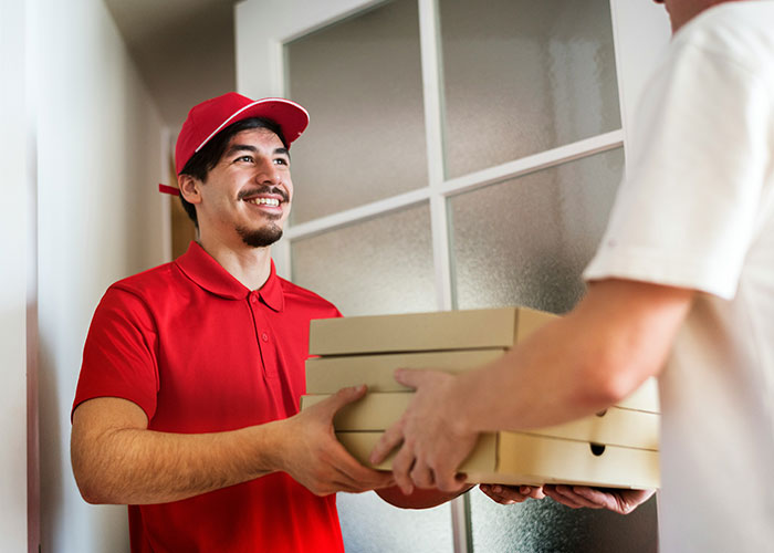 Delivery person in red uniform handing over pizza boxes, illustrating people accidentally discovering and using loopholes.