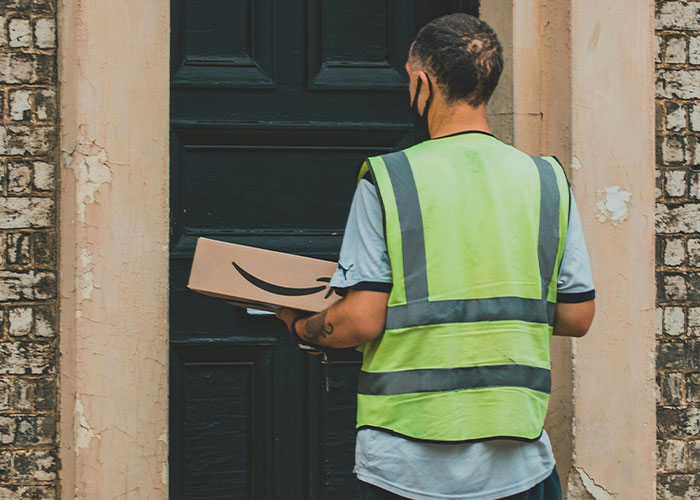 Delivery worker in a high-visibility vest holding a package at a black door, illustrating loopholes people discover.