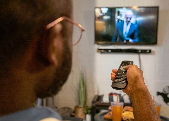 Person using a remote control to watch TV, illustrating people discovering loopholes they used the hell out of.