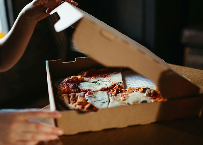 Person lifting pizza box lid to reveal partially eaten pizza, illustrating creative loopholes used in everyday situations.
