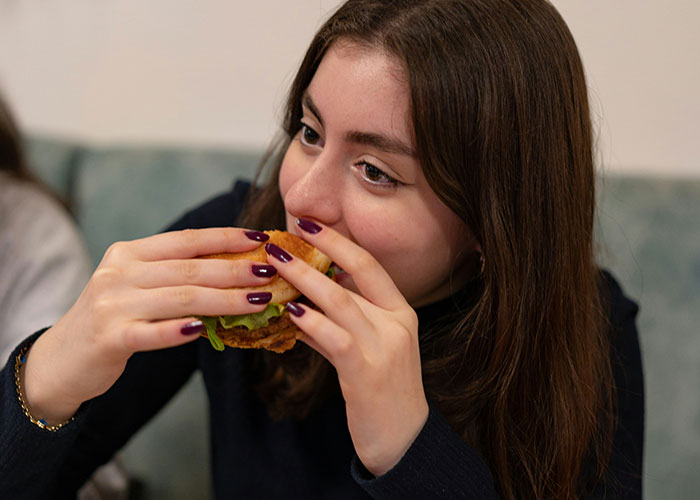 Young woman enjoying a burger, illustrating creative loopholes people accidentally discovered and used effectively.