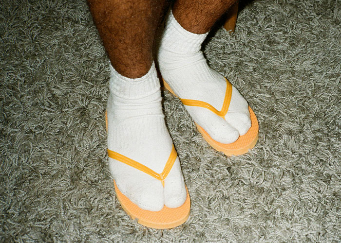 Legs wearing socks with flip-flops on a carpet, illustrating a quirky loophole discovery used creatively.