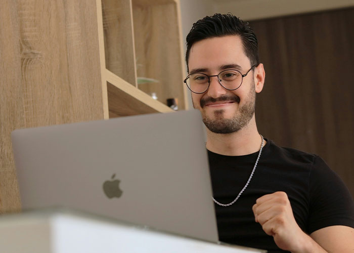 Man smiling at laptop screen, celebrating accidental discovery of loopholes for clever use in everyday situations.