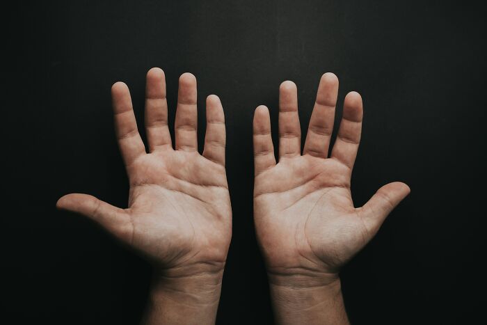 Pair of open hands against a dark background symbolizing unusual money-making hacks people have actually pulled off.