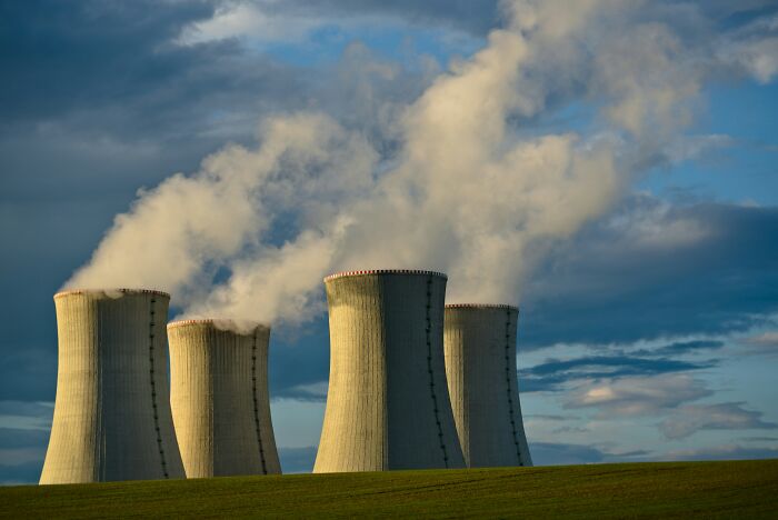 Cooling towers of a nuclear power plant emitting steam on a clear day, illustrating totally safe things causing concern.