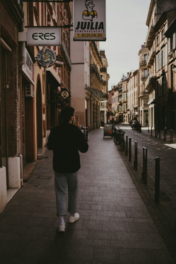 Person walking down a quiet city street, representing glitches in the matrix people experienced moments that are hard to believe.