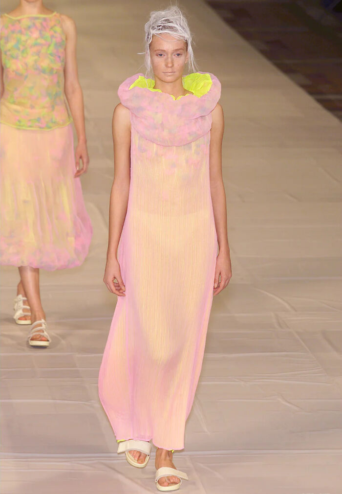 Model wearing a pastel-colored bloated cupcake maternity dress on runway, highlighting exaggerated fashion design and price controversy.