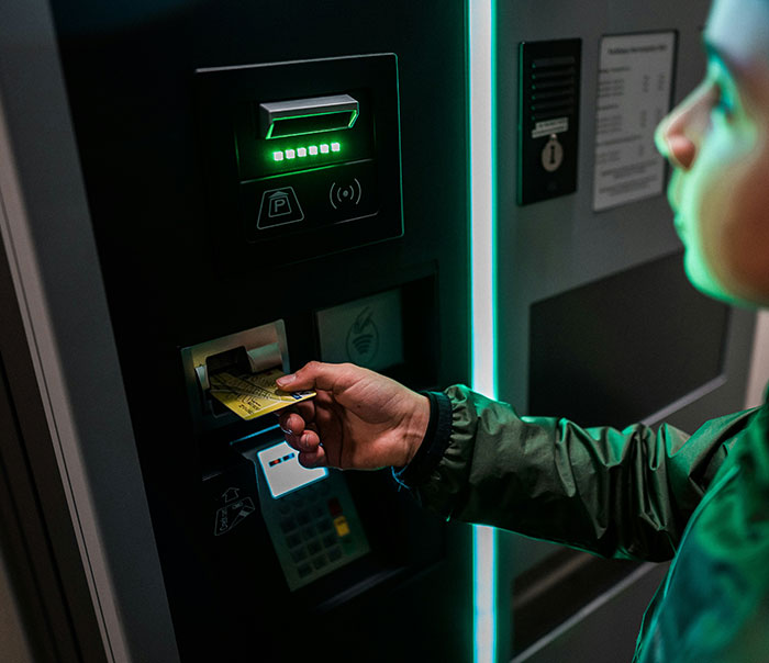 Person using a parking ticket machine at night, illustrating one of the most stupid ways men get caught by their partners. - 4