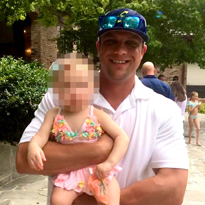 Man in sunglasses holding child outdoors, related to father assaults friend over refusal to share breast milk.