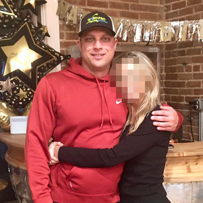 Man in red hoodie and cap posing with woman in black sweater at a casual indoor celebration with star decorations.