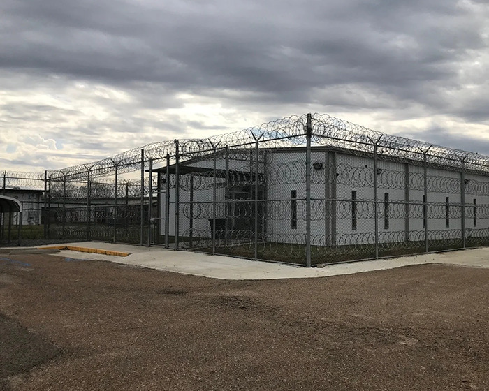 Prison building surrounded by barbed wire fence under cloudy sky, related to father-of-two assault case.