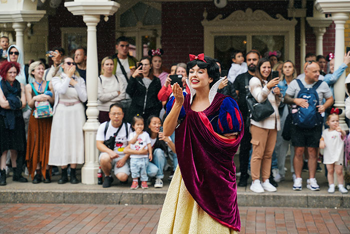 Woman dressed as Snow White entertaining a crowd, illustrating family hosting divorcing friend and nasty scents in home story.