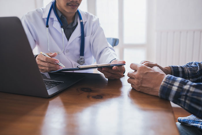 Doctor consulting a man about his sleep disorder and medical mystery during a discussion at a wooden desk.