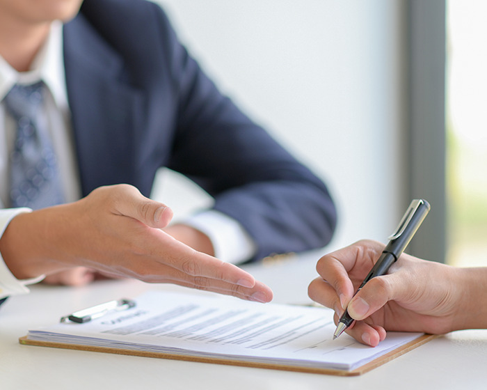 Person in suit gesturing while another signs gym membership contract highlighting high-cost gym membership issue. Person in suit gesturing while another signs gym membership contract highlighting high-cost gym membership issue.