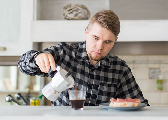 Man pouring coffee at breakfast, reflecting doubts in relationship and expecting special treatment from girlfriend on birthday.