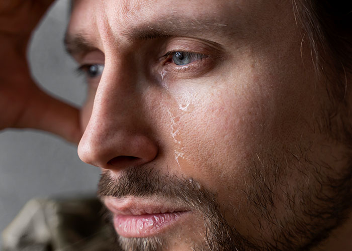 Close-up of a man with a tear on his cheek, reflecting doubts about his relationship and unmet birthday expectations.