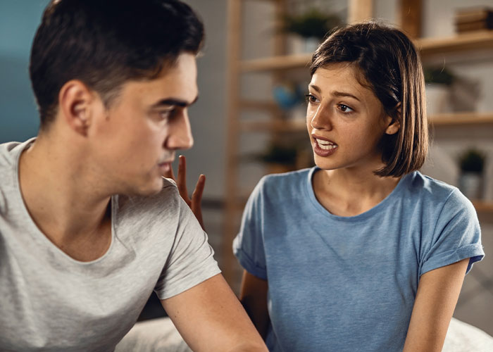 Man and woman having a serious conversation about a tattoo, with tension and emotional distress in a home setting.